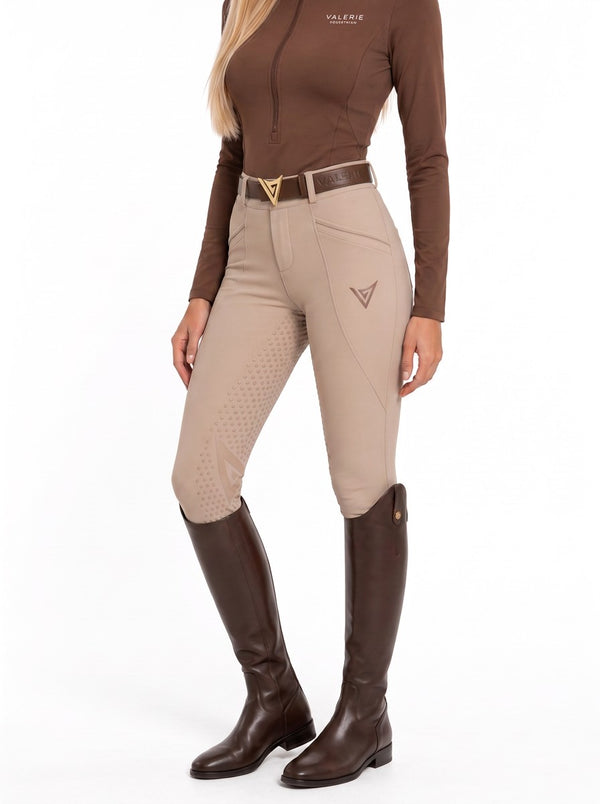 Beige competition breeches with a chocolate turtleneck and brown tall boots, three-quarter front view showing the knee grip — Valerie Equestrian Impulsion