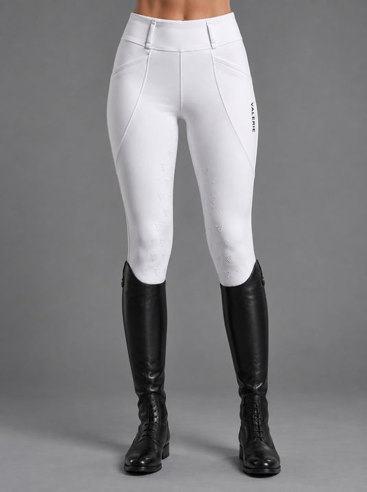 Rider in white competition leggings with a grey long-sleeve show shirt and black tall boots, full-length view — Valerie Equestrian Stride