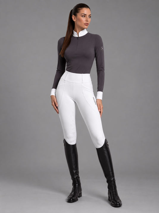Rider in white competition leggings with a grey long-sleeve show shirt and black tall boots, full-length view — Valerie Equestrian Stride
