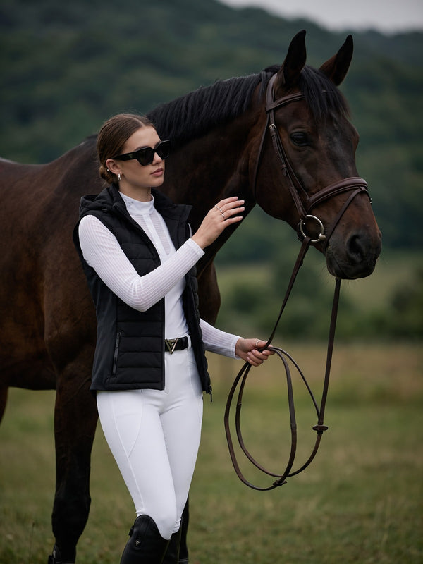 Rider in black hooded gilet with horse outdoors — Valerie Equestrian Assurance