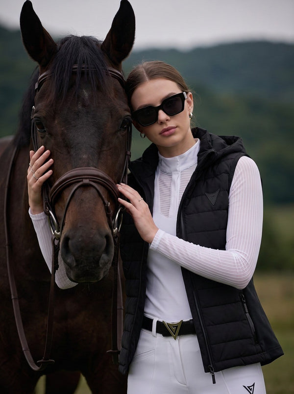 Rider in black hooded gilet beside her horse — Valerie Equestrian Assurance