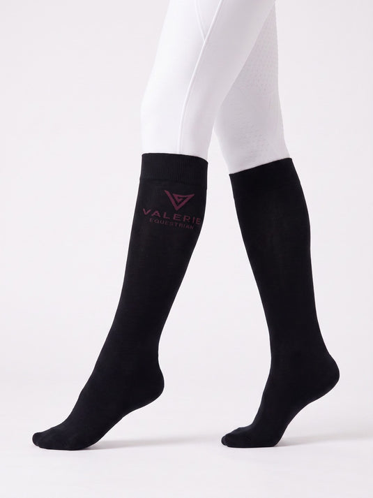 Black riding knee-highs with burgundy logo, worn with white breeches, side view — Valerie Equestrian Support